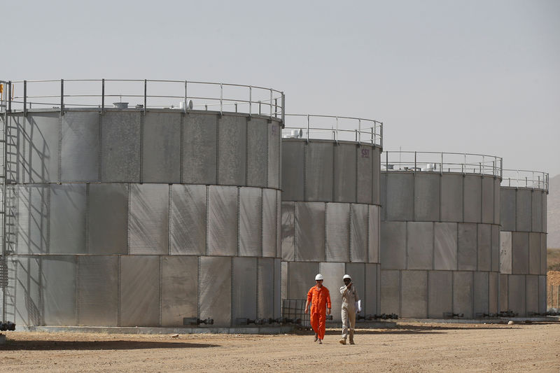 © Reuters. FILE PHOTO: Workers walk past storage tanks at Tullow Oil's Ngamia 8 drilling site in Lokichar