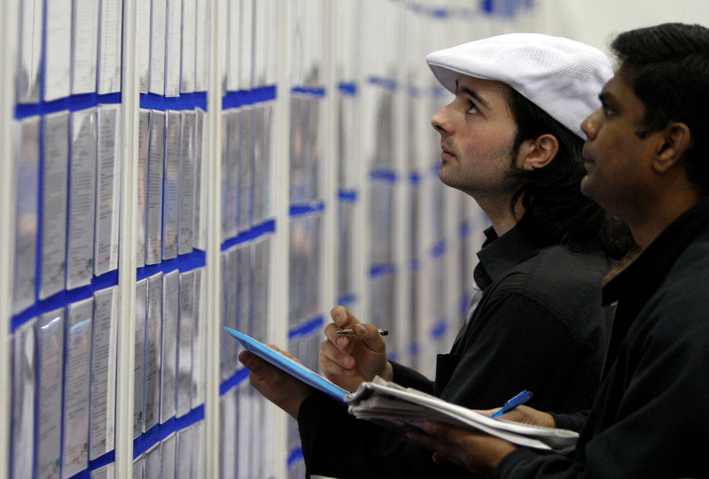 © Reuters. FILE PHOTO: People look at job listings at the Careers and Jobs Live careers fair at the ExCeL centre in London