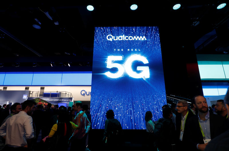 © Reuters. People walk by a video display promoting 5G connectivity at the Qualcomm booth during the 2019 CES in Las Vegas