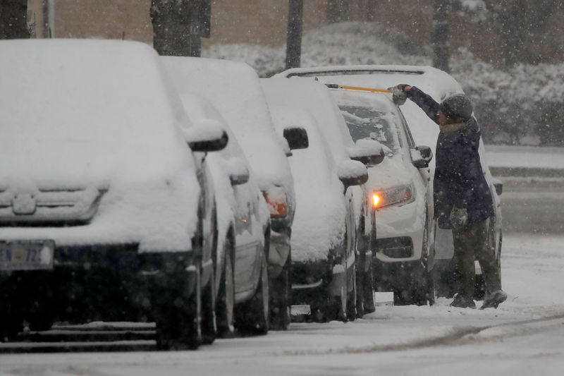 © Reuters. Morador tira neve de cima de carro em Washington