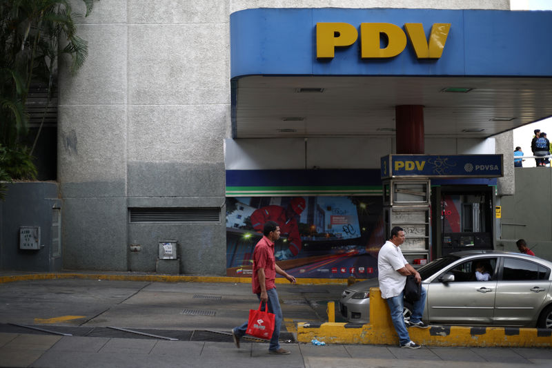 © Reuters. FILE PHOTO:  A pedestrian walks next to a PDVSA gas station in Caracas