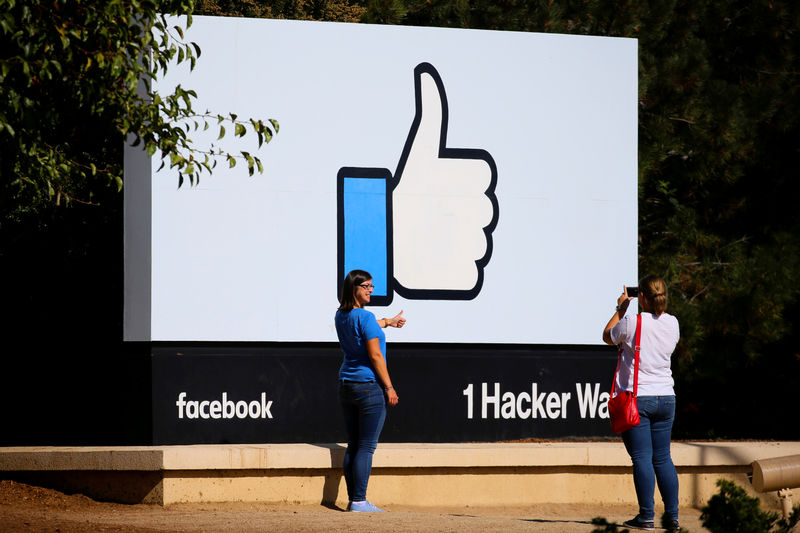 © Reuters. FILE PHOTO: Two women take photos in front of the entrance sign to Facebook headquarters in Menlo Park