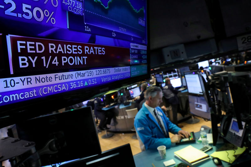 © Reuters. FILE PHOTO: A screen displays the headlines that the U.S. Federal Reserve raised interest rates as a trader works at a post on the floor of the NYSE in New York