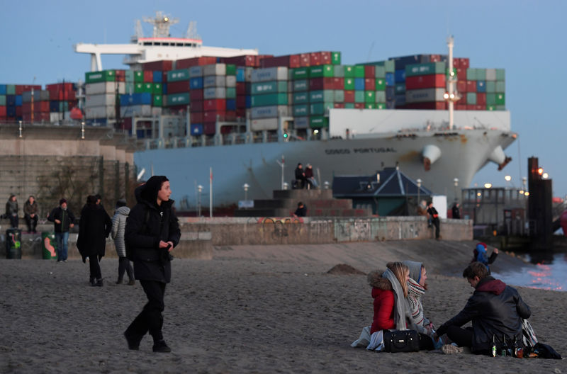 © Reuters. People enjoy the sunset in front of a container ship at the Elbe river in Hamburg