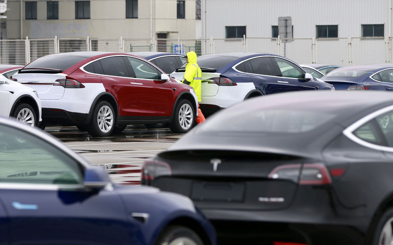 © Reuters. Worker walks next to Tesla cars at a port in Shanghai