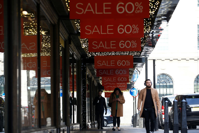 © Reuters. Pedestrians walk beneath sale signs, in London
