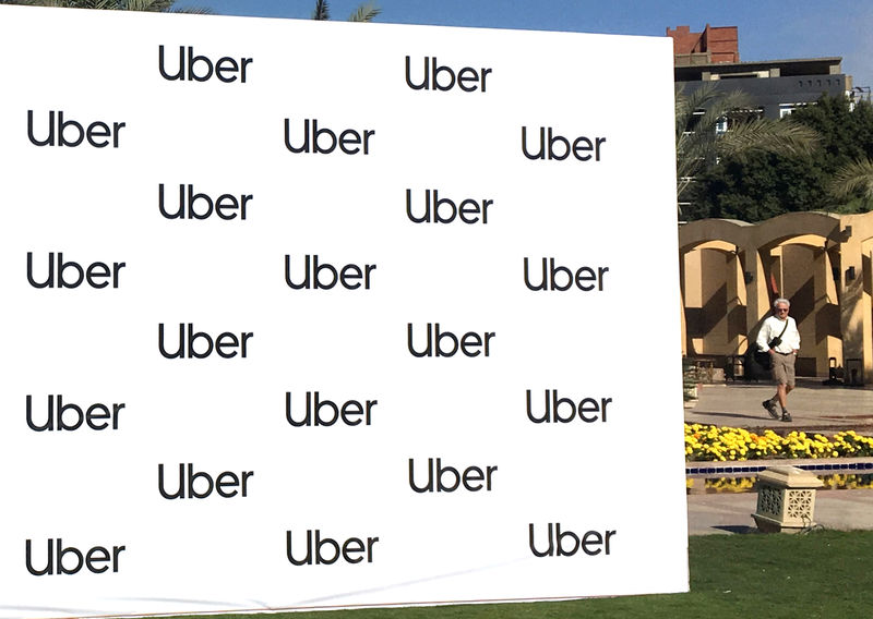© Reuters. FILE PHOTO - A man walks near a banner of ride-sharing app Uber during a news conference in Cairo