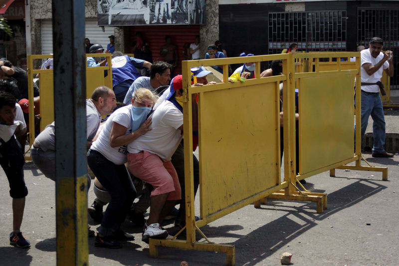 © Reuters. Demonstrators take cover while clashing with Venezuela's security forces during a rally to demand President Nicolas Maduro to allow humanitarian aid to enter the country in San Antonio del Tachira