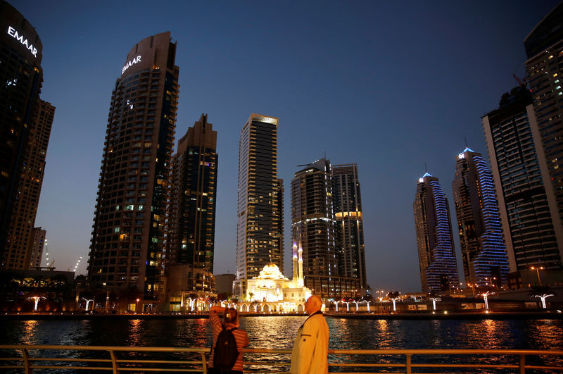 © Reuters. Tourist take photos of a mosque across the Dubai Marina, surrounded by high towers of hotels, banks and office buildings, in Dubai