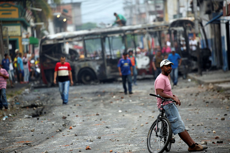 © Reuters. Foto del domingo de un grupo de personas caminando cerca de los restos de un bus quemado durante los enfrentamientos entre manifestantes venezolanos y las fuerzas de seguridad en Ureña