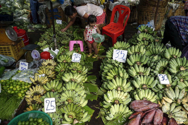 © Reuters. A mother and her daughter shop for bananas at a market in Bangkok