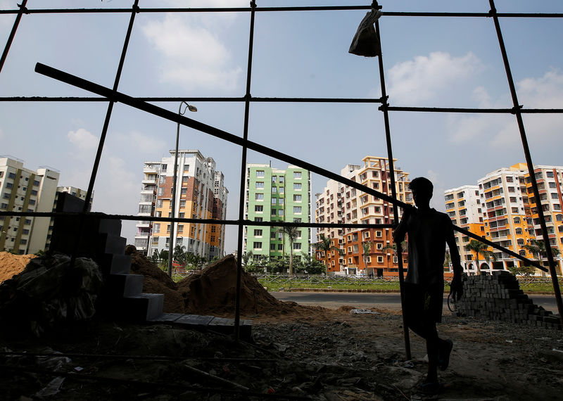 © Reuters. FILE PHOTO:  A labourer carries an iron pipe at the construction site of a residential complex on the outskirts of Kolkata