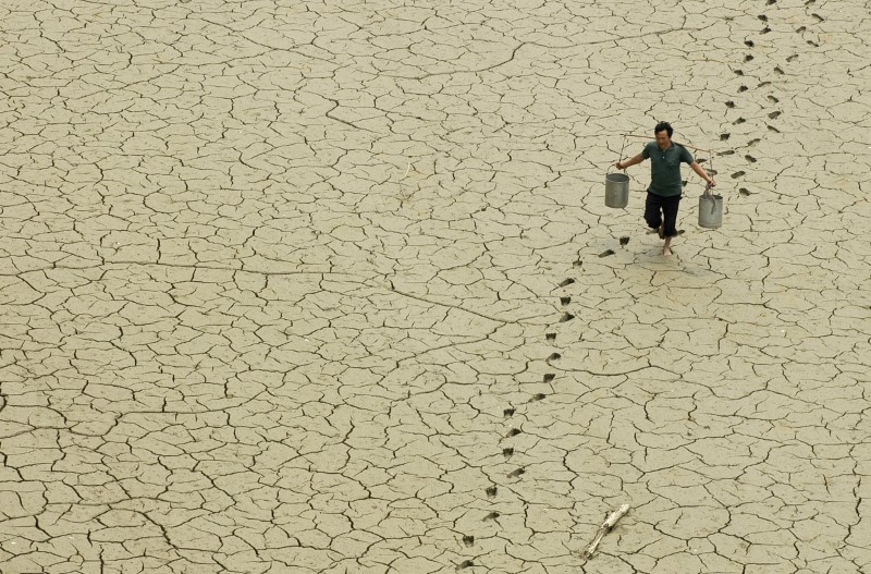 © Reuters. Un agricultor camina por una laguna seca en las afueras de Baokang