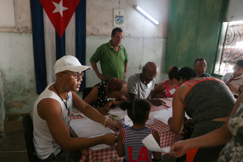 © Reuters. Foto del domingo de autoridades electorales en La Habana controlando el documento de un votante en el referendo constitucional de Cuba.