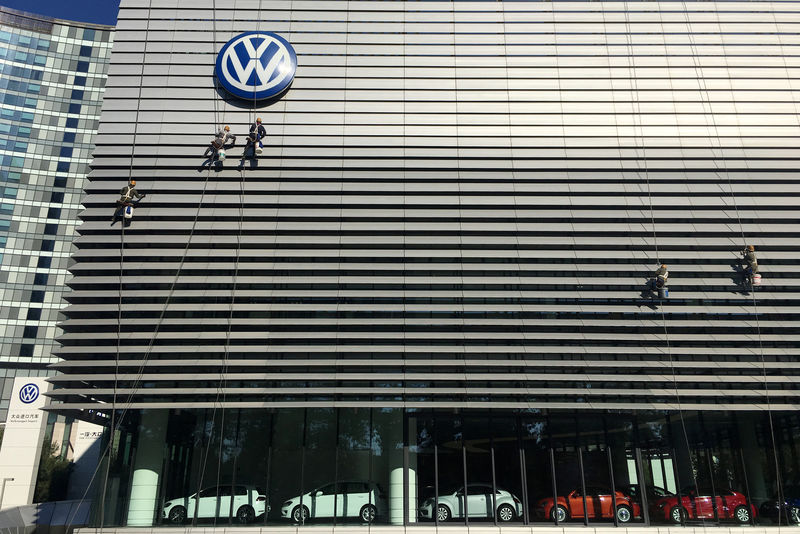 © Reuters. Workers clean the facade of a car showroom under a Volkswagen logo in Beijing