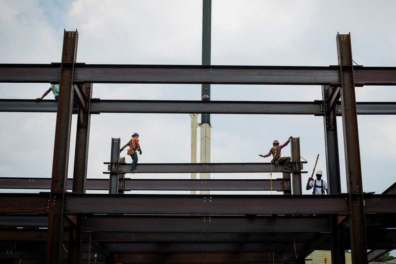 © Reuters. FILE PHOTO: Iron workers install steel beams during a hot summer day in New York