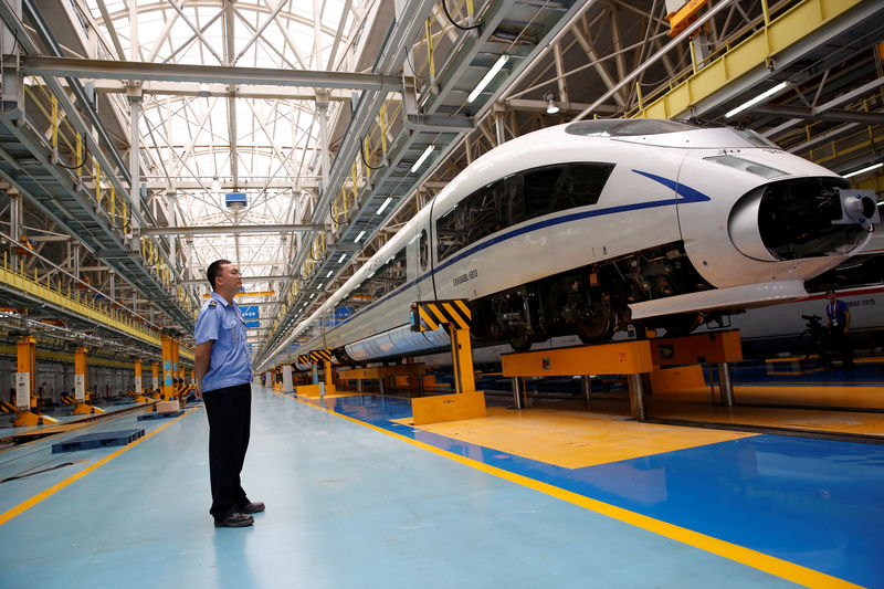 © Reuters. FILE PHOTO: A worker stands next to a high-speed train at the maintenance and repair depot of China Railway High-speed (CRH) rail service during a media tour in Beijing