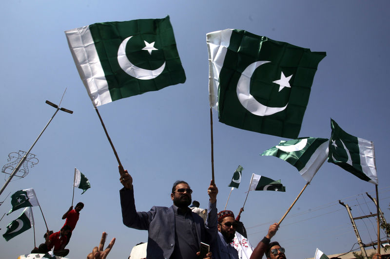 © Reuters. Pessoas carregam bandeiras do Paquistão em Lahore para comemorar que forças do país abateram dois caças indianos