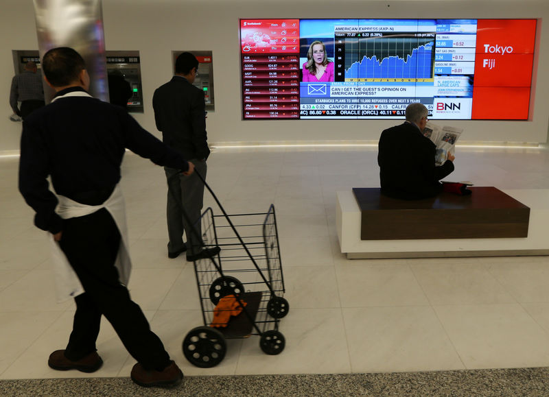 © Reuters. Passersby watch the performance of stocks on a financial news television screen in the business district of Toronto