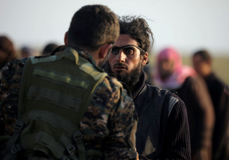 © Reuters. FILE PHOTO: A fighter from Syrian Democratic Forces (SDF) checks a man near the village of Baghouz, Deir Al Zor province