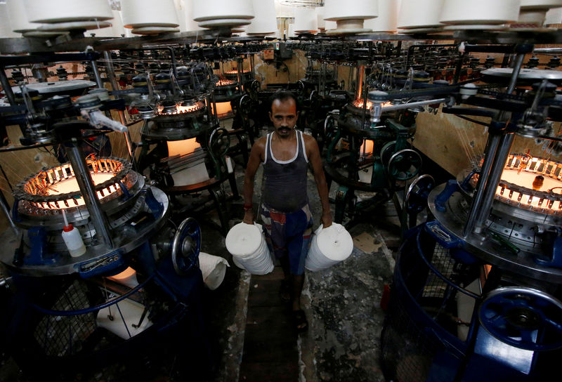 © Reuters. FILE PHOTO:  An employee carries cloth rolls inside an undergarment factory in Kolkata