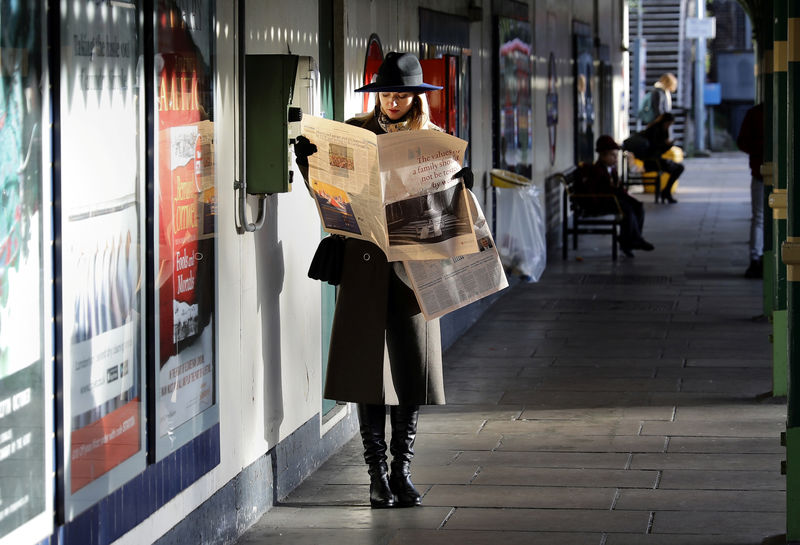 © Reuters. A woman reads a newspaper whilst waiting for a tube train on an autumn morning in London