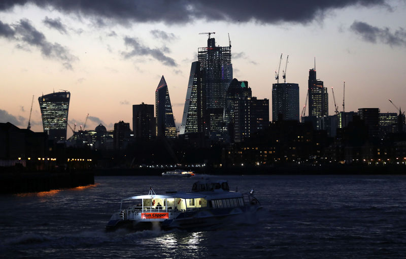 © Reuters. A river boat cruises down the River Thames as the sun sets behind the Canary Wharf financial district of London