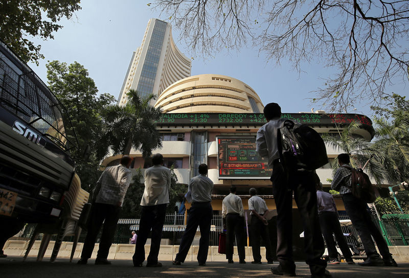 © Reuters. People look at a screen displaying the Sensex results on the facade of the Bombay Stock Exchange (BSE) building in Mumbai