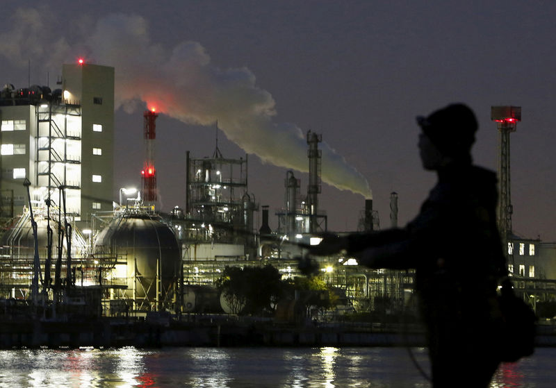 © Reuters. FILE PHOTO - Smoke is emitted from a chimney as a man fishes at the Keihin industrial zone in Kawasaki