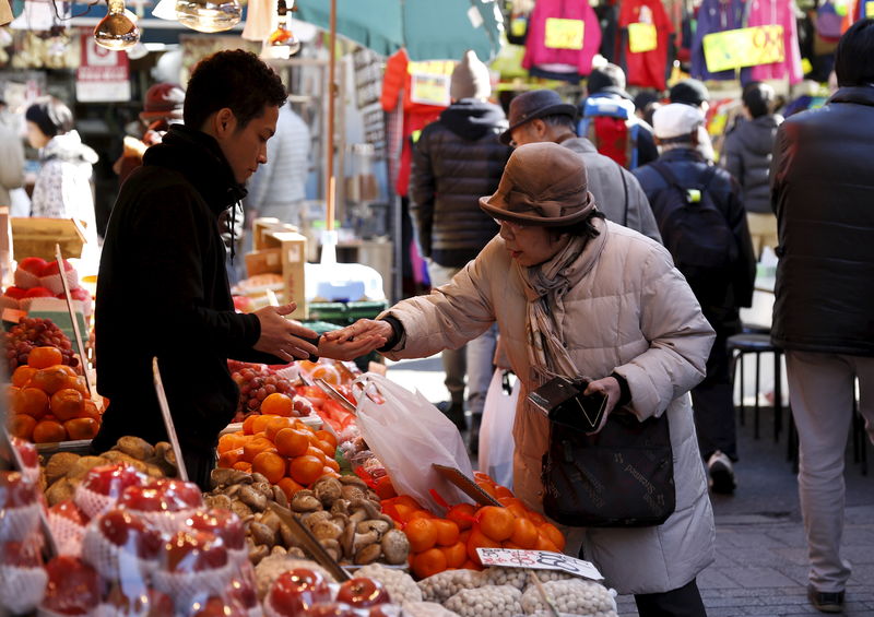 © Reuters. A woman pays money as she buys fruits outside a vegetable store at Ameyoko shopping district in Tokyo