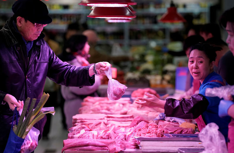 © Reuters. Un hombre compra carne de cerdo de un vendedor en un mercado en Pekín