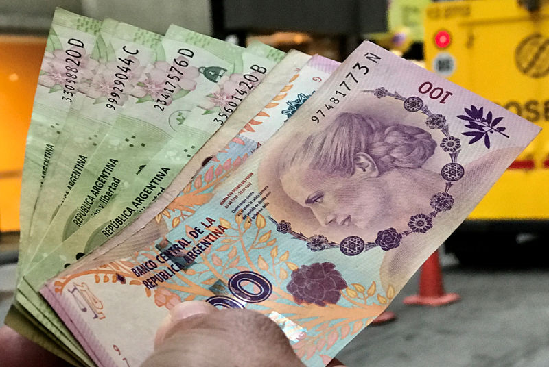 © Reuters. A man shows Argentine pesos outside a bank in Buenos Aires' financial district