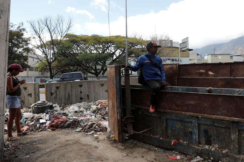 © Reuters. A man sits on a rubbish container in Caracas