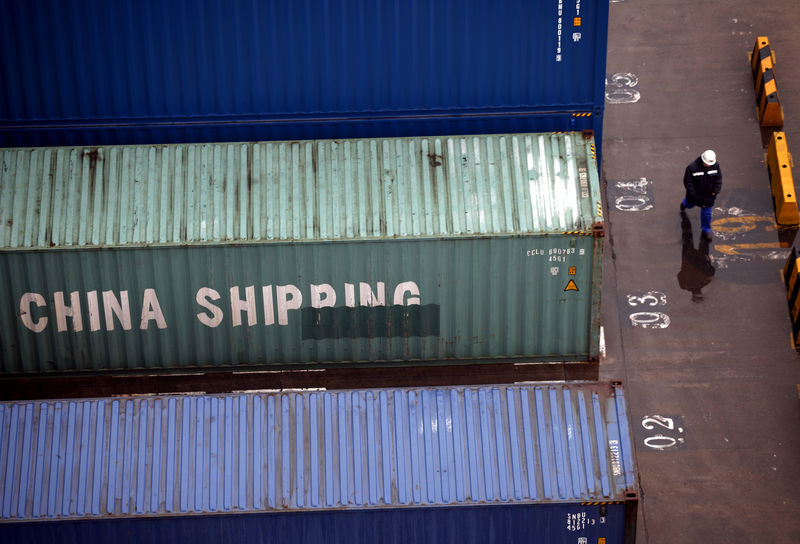 © Reuters. FILE PHOTO: A worker walks past shipping containers at the Port of Shanghai