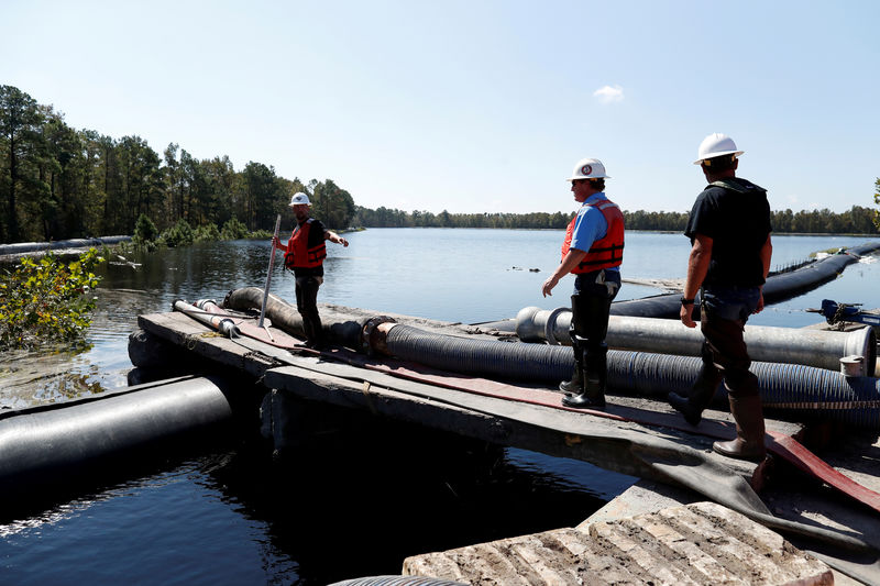 © Reuters. FILE PHOTO: Santee Cooper workers check the water levels around a 6000 foot long Aqua Dam built to keep sediment from a coal ash retention pond from going into the flooded Waccamaw River in the aftermath of Hurricane Florence in Conway