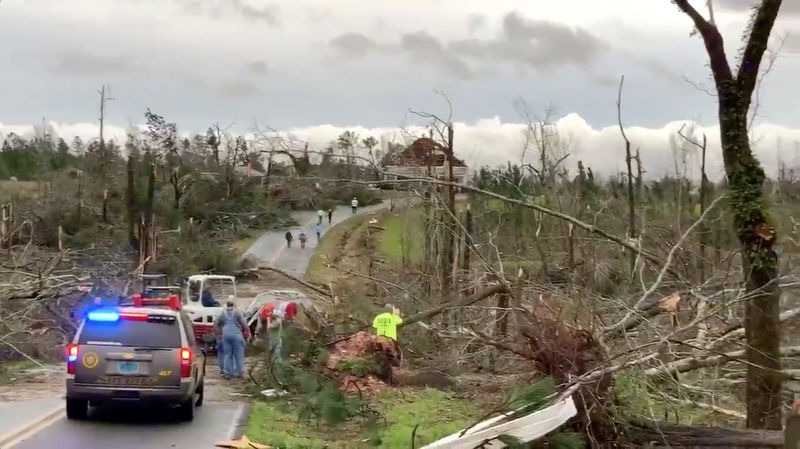 © Reuters. People clear fallen trees and debris on a road following a tornado in Beauregard, Alabama, U.S. in this March 3, 2019 still image obtained from social media video