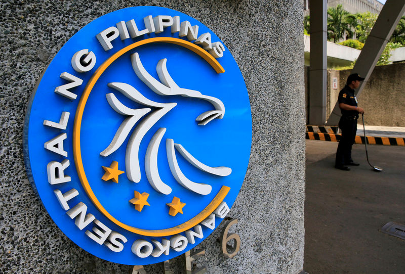 © Reuters. FILE PHOTO - Security guard stands beside a logo of the Bangko Sentral ng Pilipinas (Central Bank of the Philippines) posted at the main gate in Manila