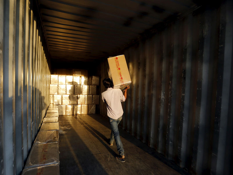 © Reuters. FILE PHOTO - A worker loads goods into a container at Thar Dry Port in Sanand