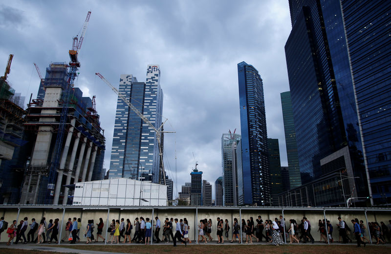 © Reuters. FILE PHOTO - Office workers walk to the train station during evening rush hour in the financial district of Singapore