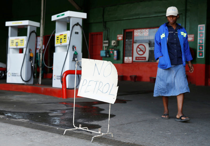 © Reuters. FILE PHOTO: A woman walks past a "No Petrol" sign at a fuel station in Harare