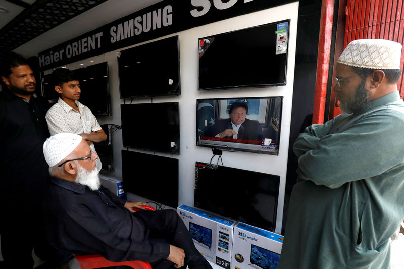 © Reuters. FILE PHOTO: Shopkeepers watch the speech of Pakistani Prime Minister Imran Khan, after Pakistan shot down two Indian military aircrafts, at a shop selling television screens in Karachi