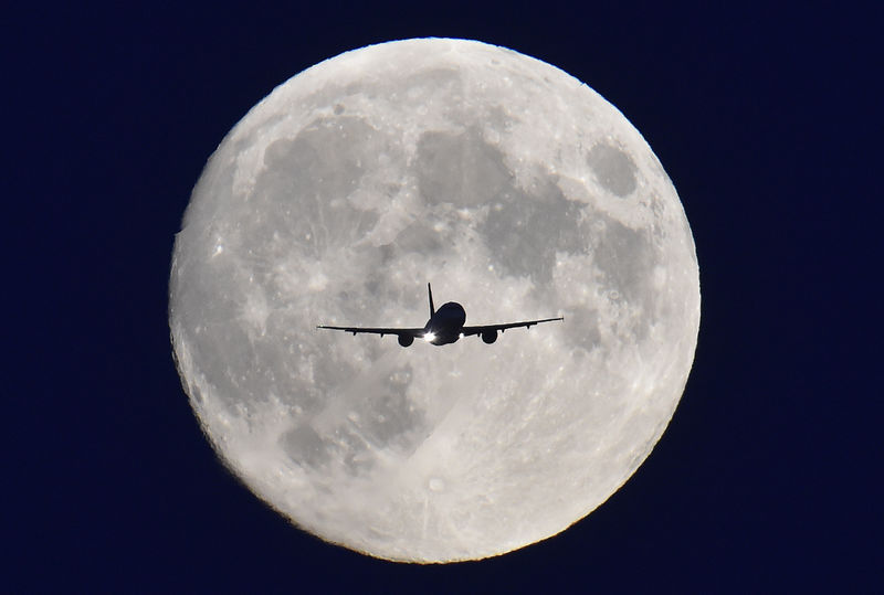 © Reuters. A passenger plane passes in front of the full moon as it makes a final landing approach to Heathrow Airport in west London