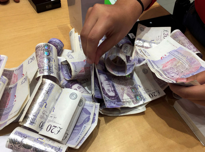 © Reuters. A shop assistant counts piles of British Pound Sterling banknotes at an Apple store in London