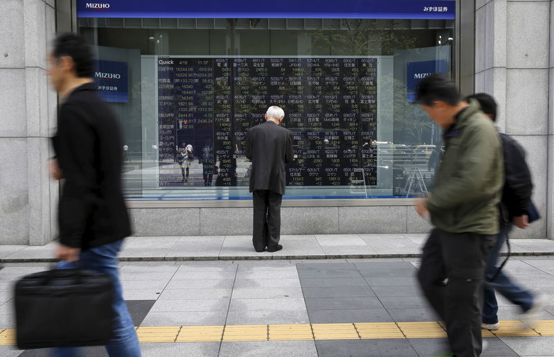 © Reuters. FILE PHOTO: Man looks at a stock quotation board outside a brokerage in Tokyo