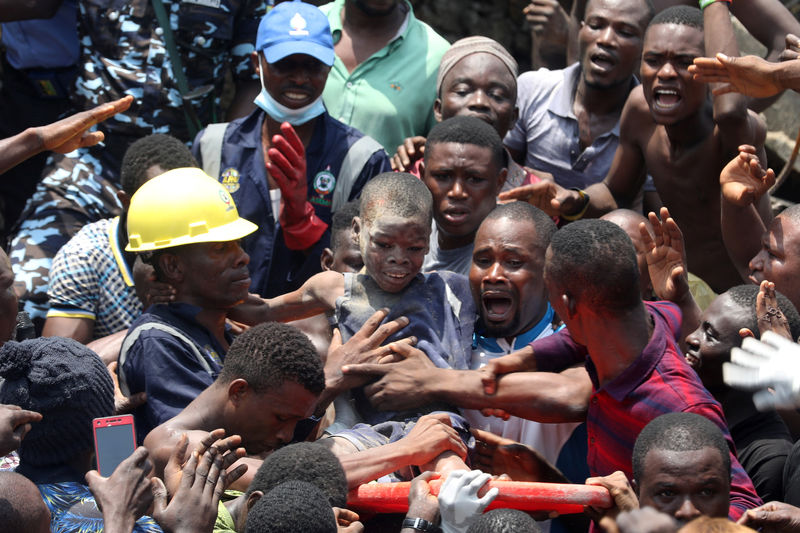 © Reuters. Homens carregam menino retirado de escombros em escola que desmoronou em Lagos