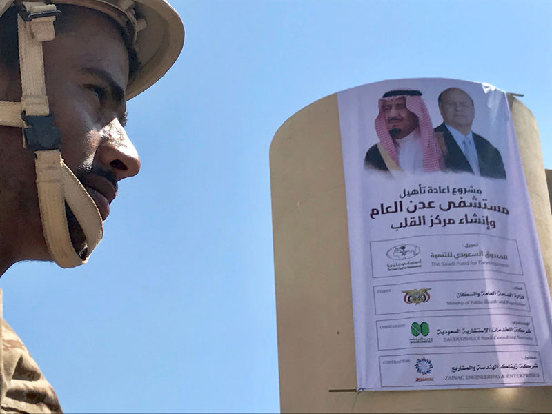 © Reuters. FILE PHOTO: Yemeni soldier near a poster portraying Saudi Arabia's King Salman bin Abdulaziz Al Saud and Yemen's President Abdrabbuh Mansur Hadi outside a hospital renovated by Saudi Arabia in Aden