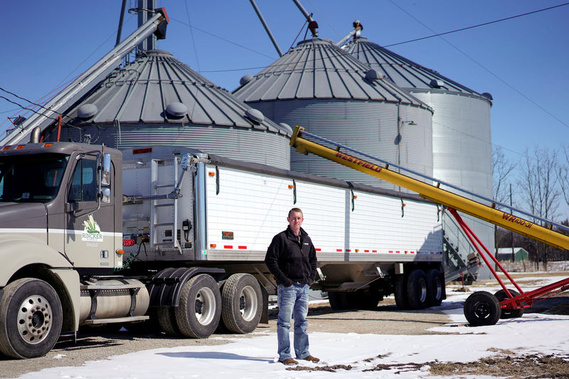 © Reuters. Soybean farmer Austin Rincker poses for a photograph near a grain truck and storage bins at his farm in Moweaqua Illinois