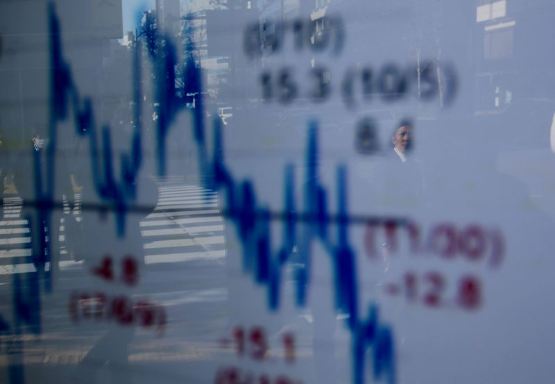 © Reuters. FILE PHOTO : A man is reflected on an electronic board showing a graph analyzing recent change of Nikkei stock index outside a brokerage in Tokyo