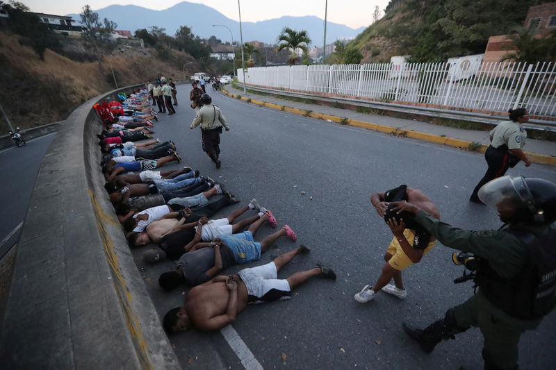 © Reuters. People detained by security forces lie on the street after looting broke out during an ongoing blackout in Caracas