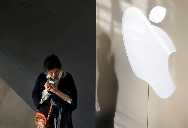 © Reuters. FILE PHOTO: A woman holds her phone near an Apple company logo in Beijing